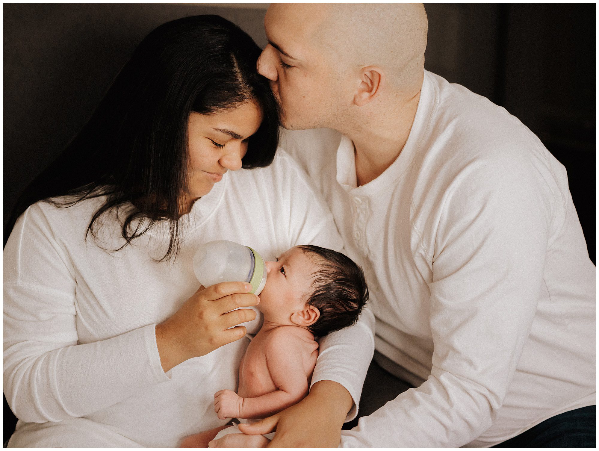New mom and dad bottle feeding newborn baby boy during lifestyle in home session in Murfreesboro TN