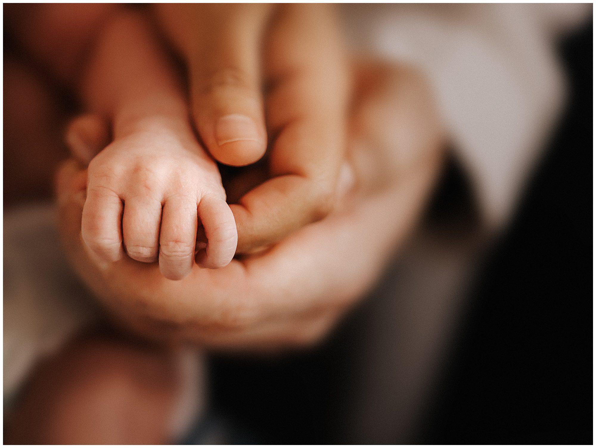 Newborn baby’s hand with moms hand and dads hand