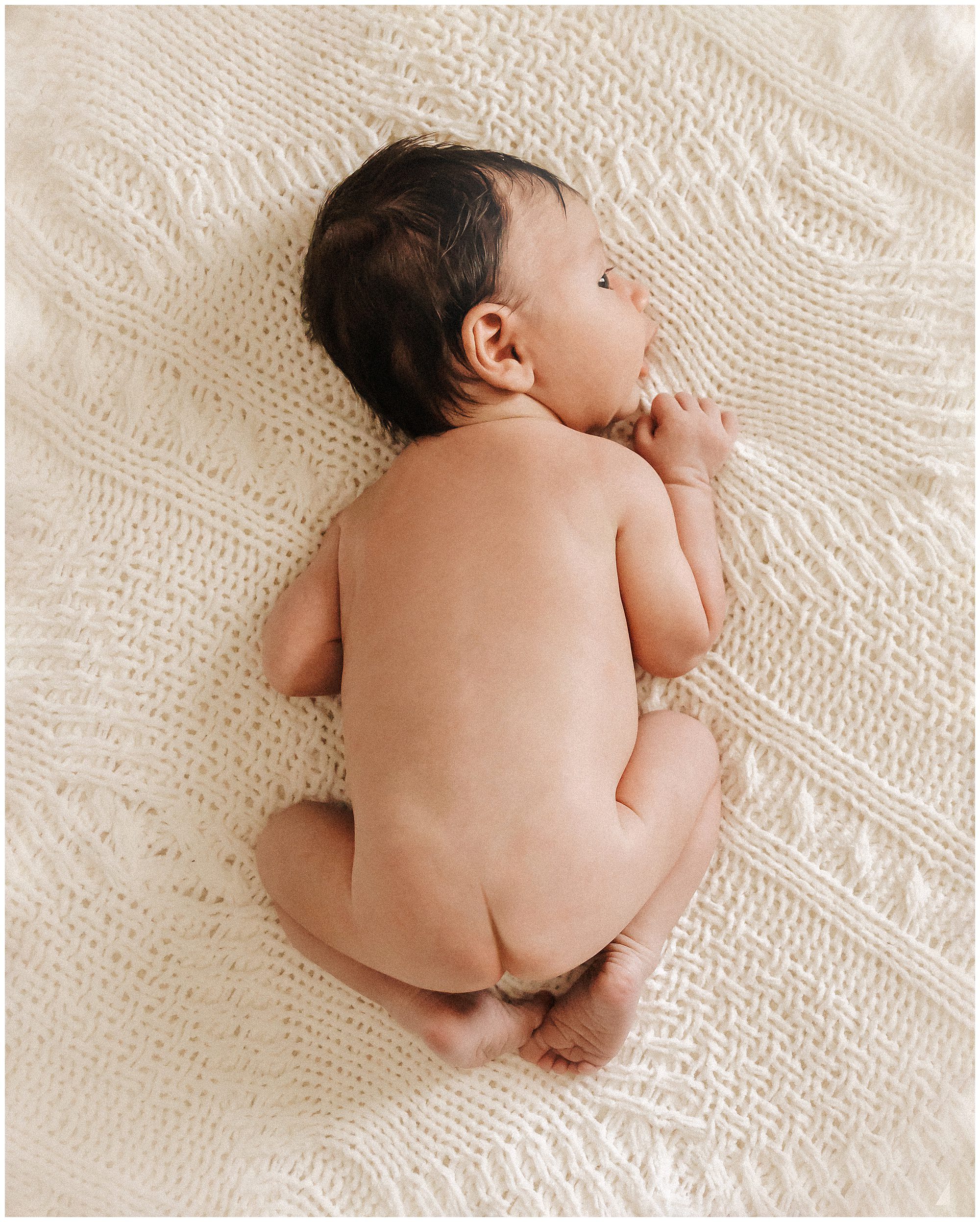 Naked Newborn Baby Boy with Dark Hair during Lifestyle Newborn Session