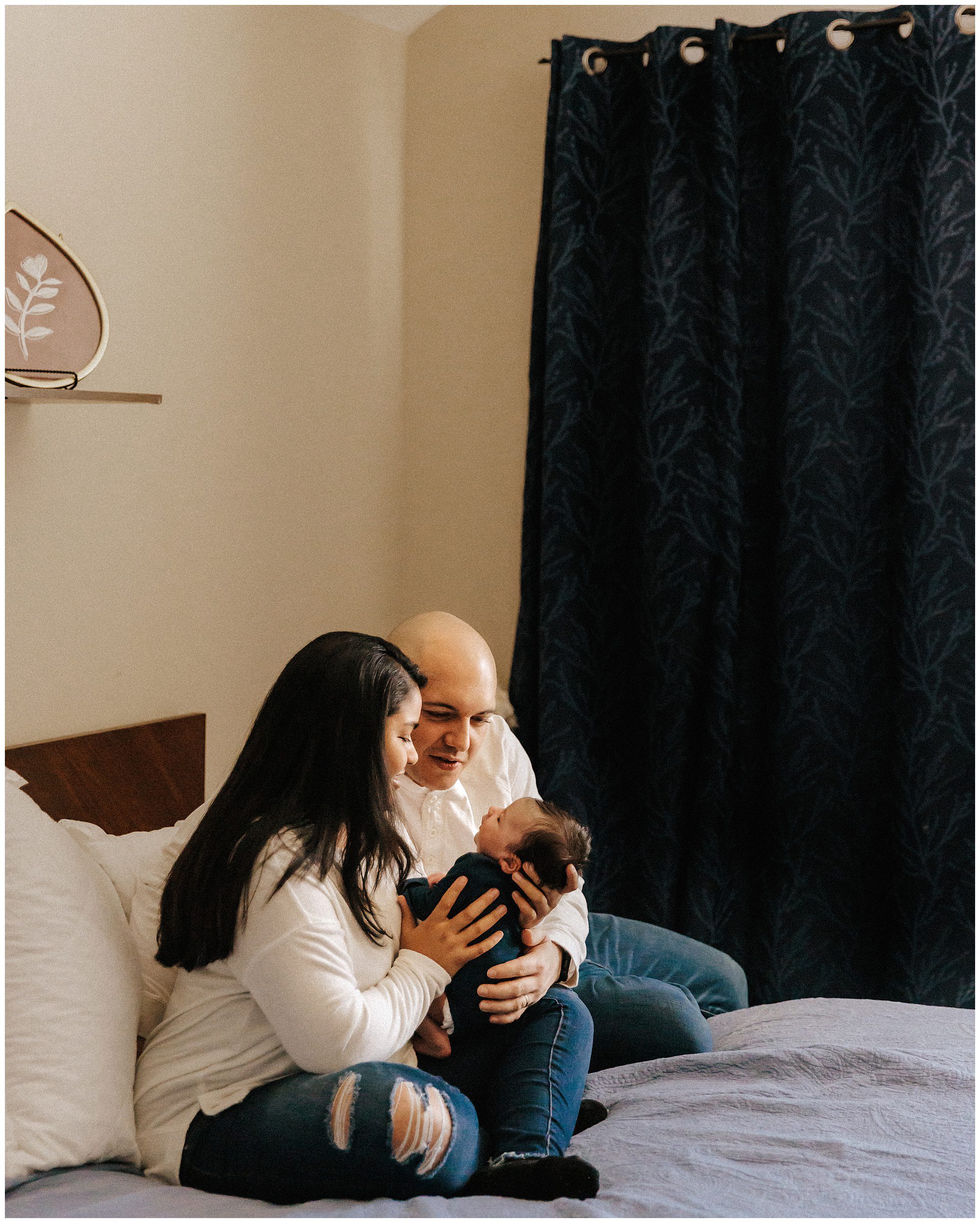 New parents sitting on bed with newborn baby during in home newborn session in Murfreesboro
