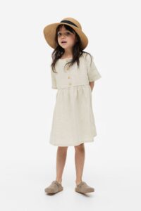 Product photo of a little girl wearing an off white short sleeve dress