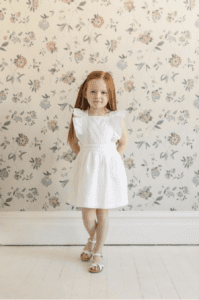 Product Photograph of little girl with red hair wearing a white ruffle dress