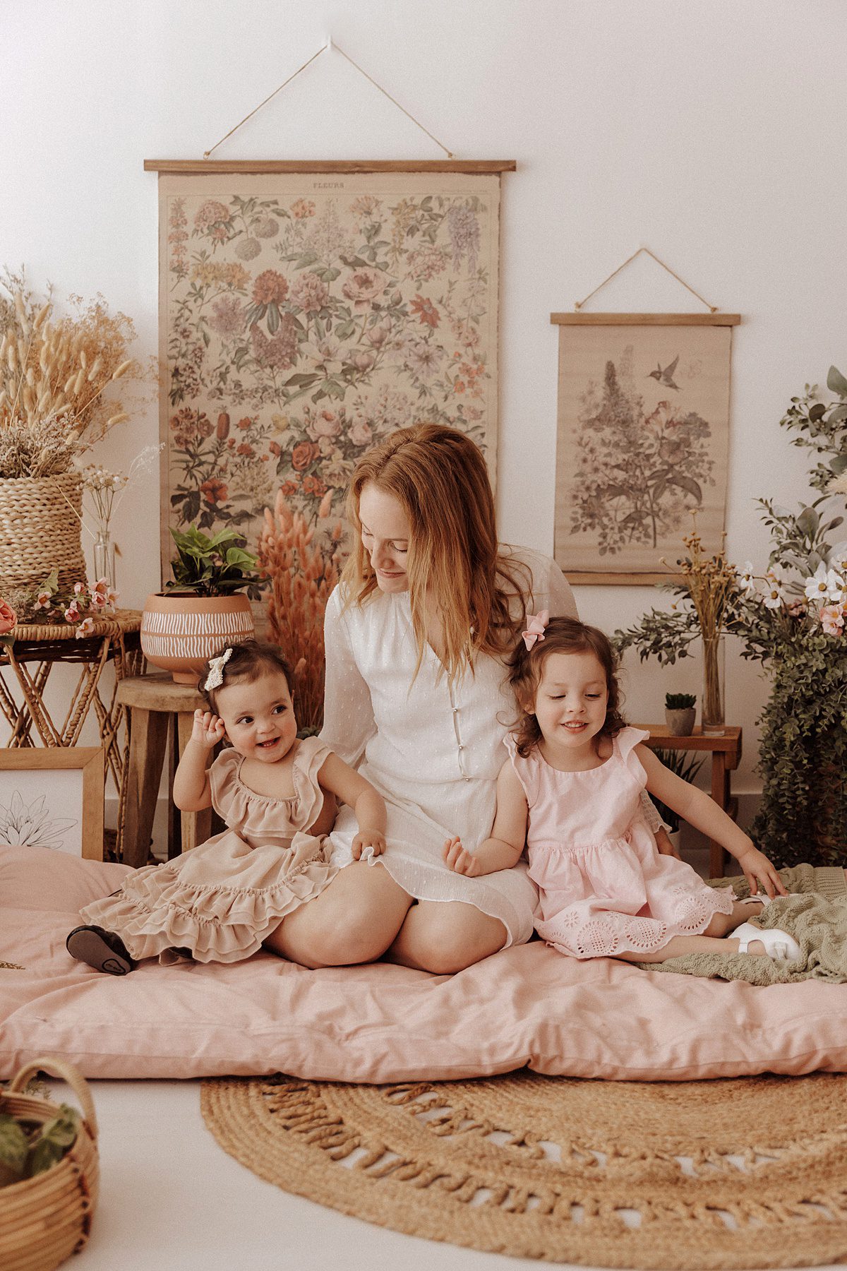 A mother sits on the floor with her two daughters 