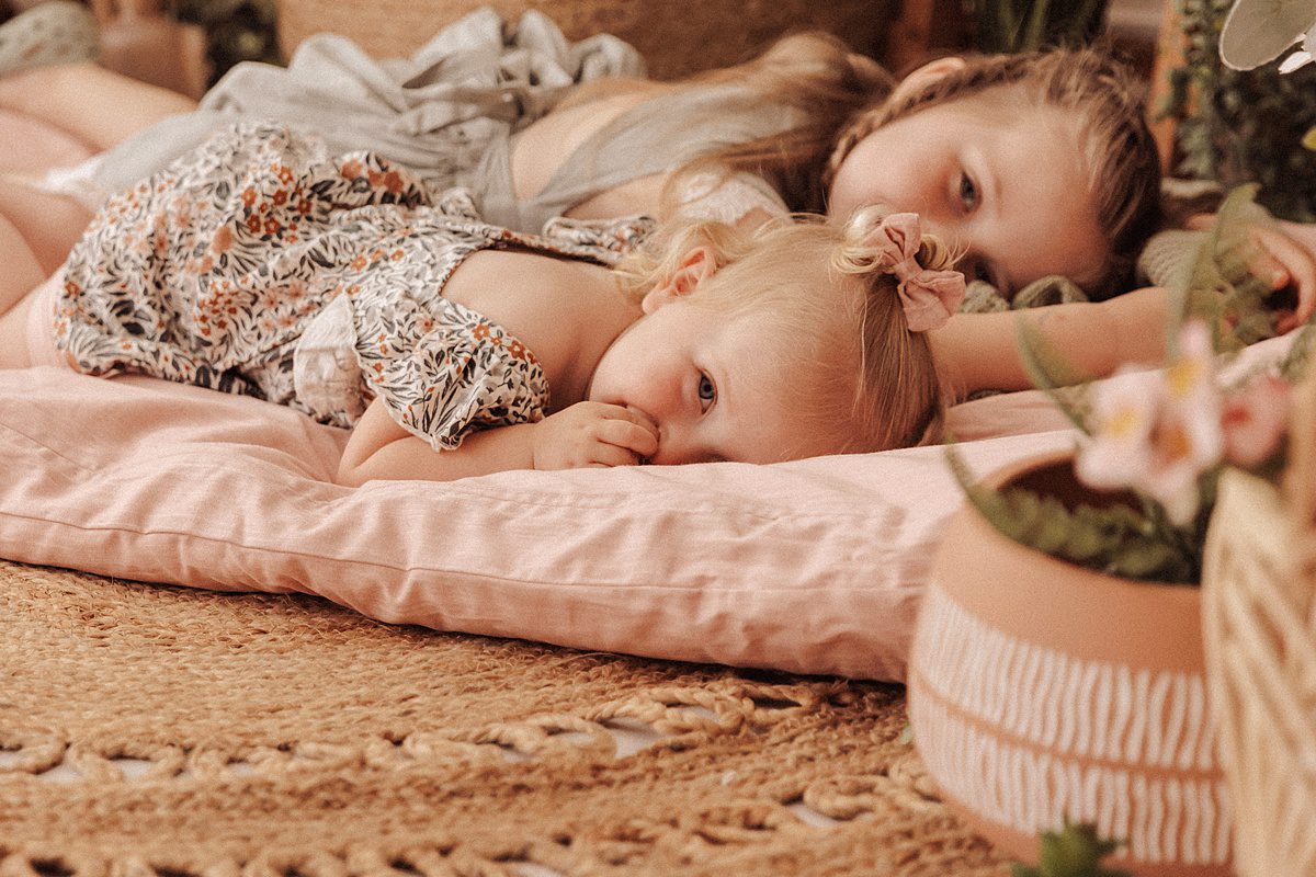 Two little girls lay together on a pink mat